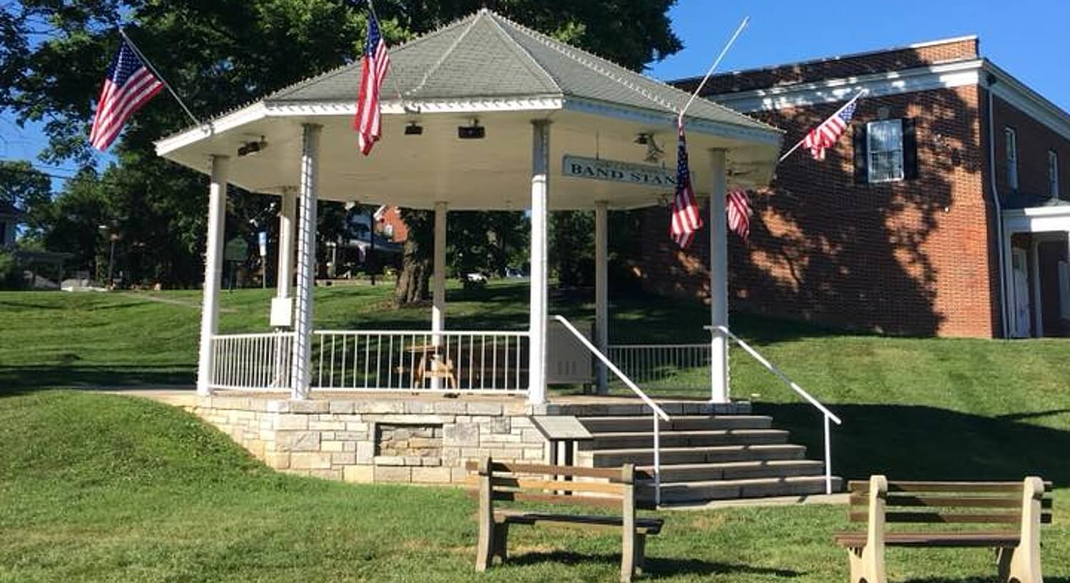 	Outdoor bandstand gazebo with American flags surrounded by green lawn