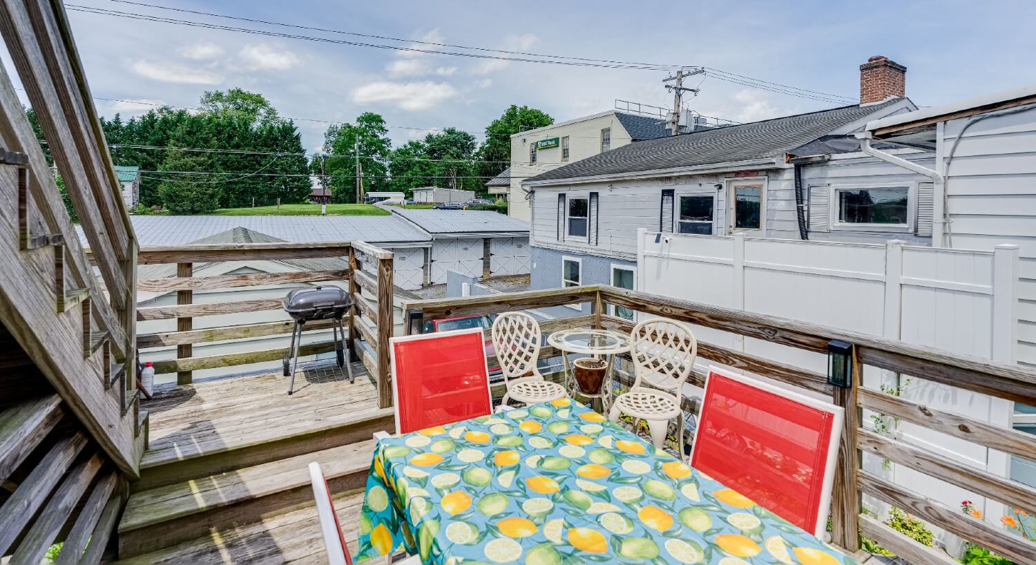 Outdoor deck patio with table and chairs and small BBQ grill