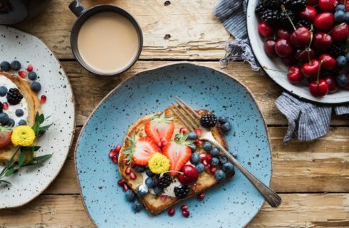 Colorful plates with breakfast toast and a bowl full of fresh fruit and berries