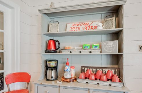 Tall grey hutch with shelves holding items for morning coffee