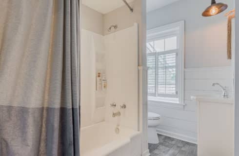 Bathroom with standup shower and tub, white shiplap detail and vanity with decorative lamp above